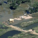 An oil storage tank on a well pad lies toppled by flood waters in Weld County