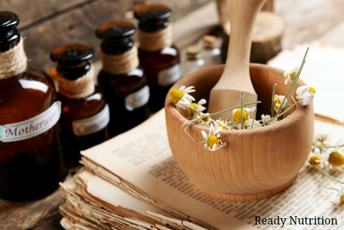 Old book with dry flowers in mortar and bottles on table close up Natural Medicine